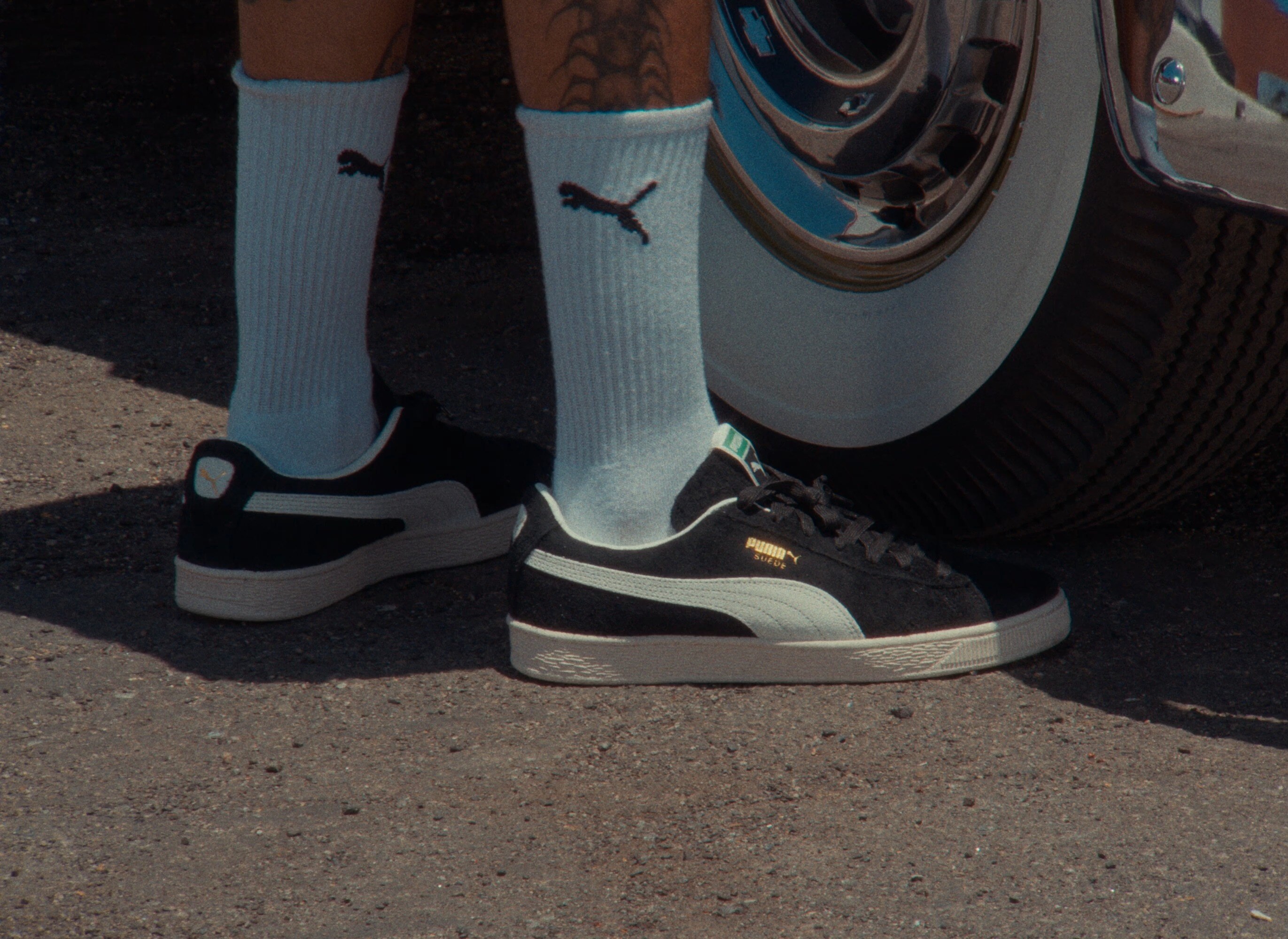 Puma Suede sneakers beside a car wheel, from the WSS back to school announcement for the Cuco meet and greet on August 29.