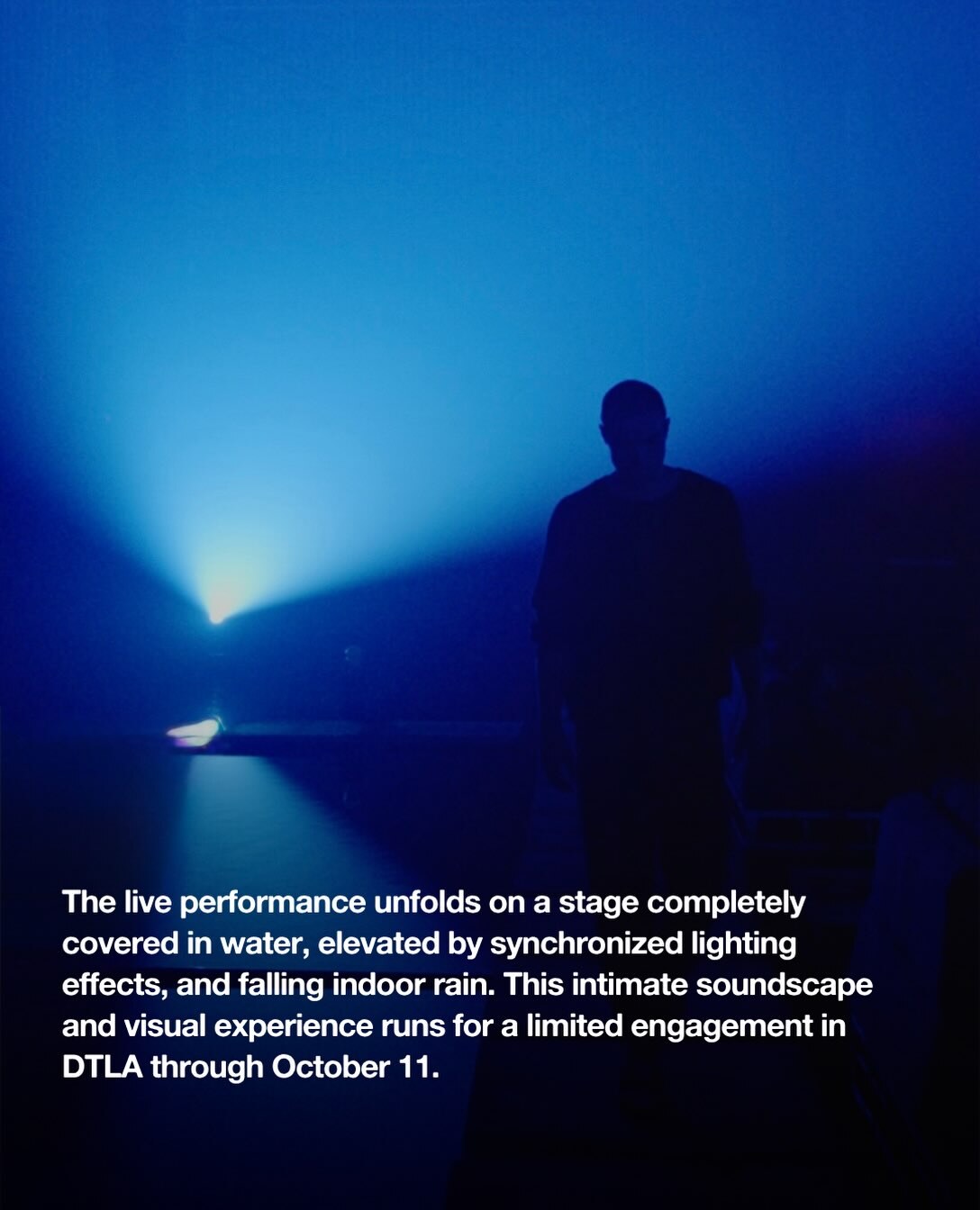 Emmit Fenn silhouetted over the water stage for The Light We Leave Behind, an indoor rain, light and sound experience in the Arts District.