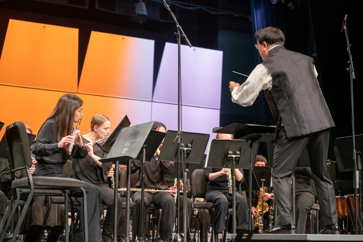 A conductor performs with a large group of instrumentalists at UCLA's Schoenberg hall