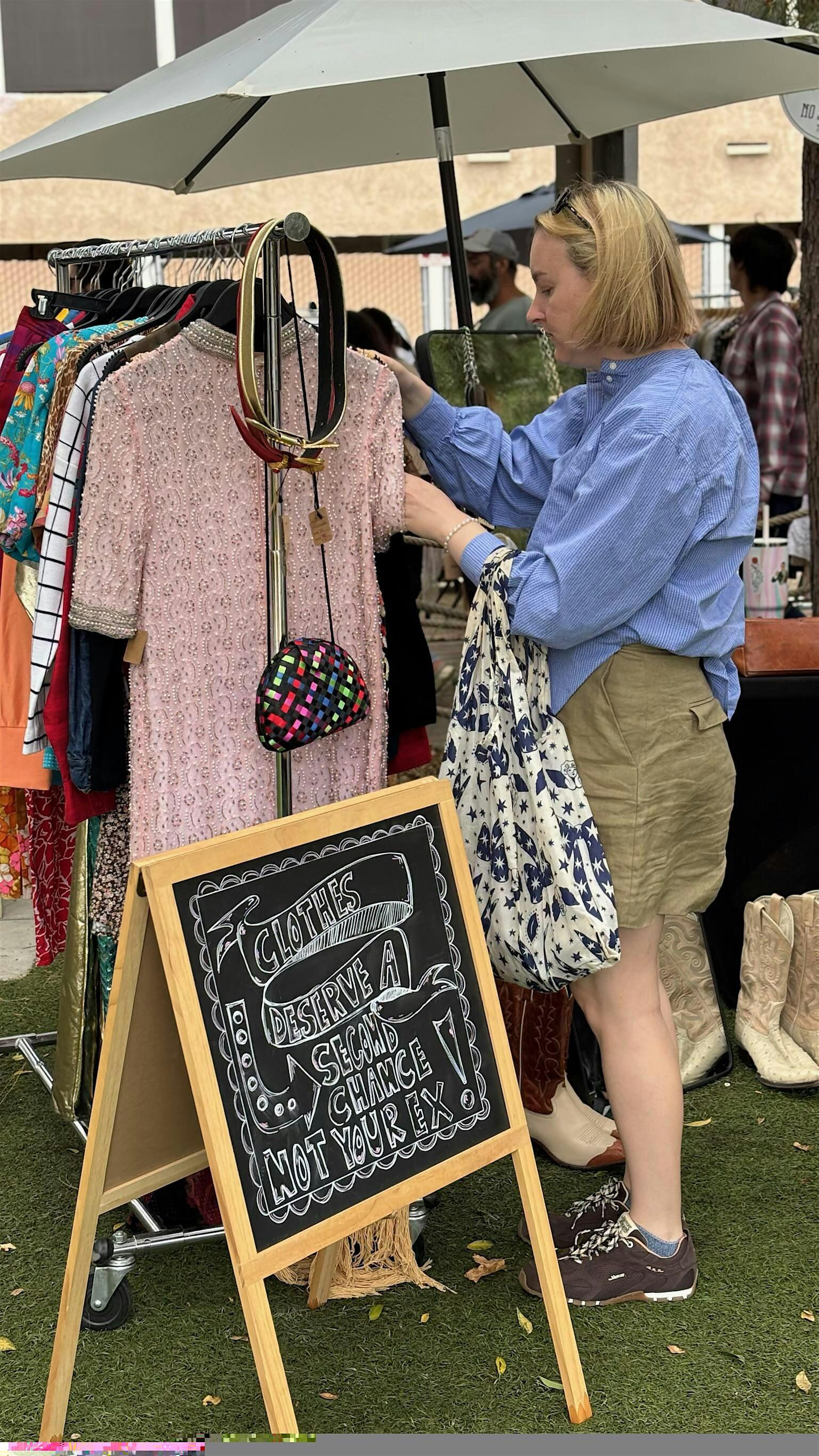 A shopper browses a rack of vintage clothing at an outdoor Second Time Around market.