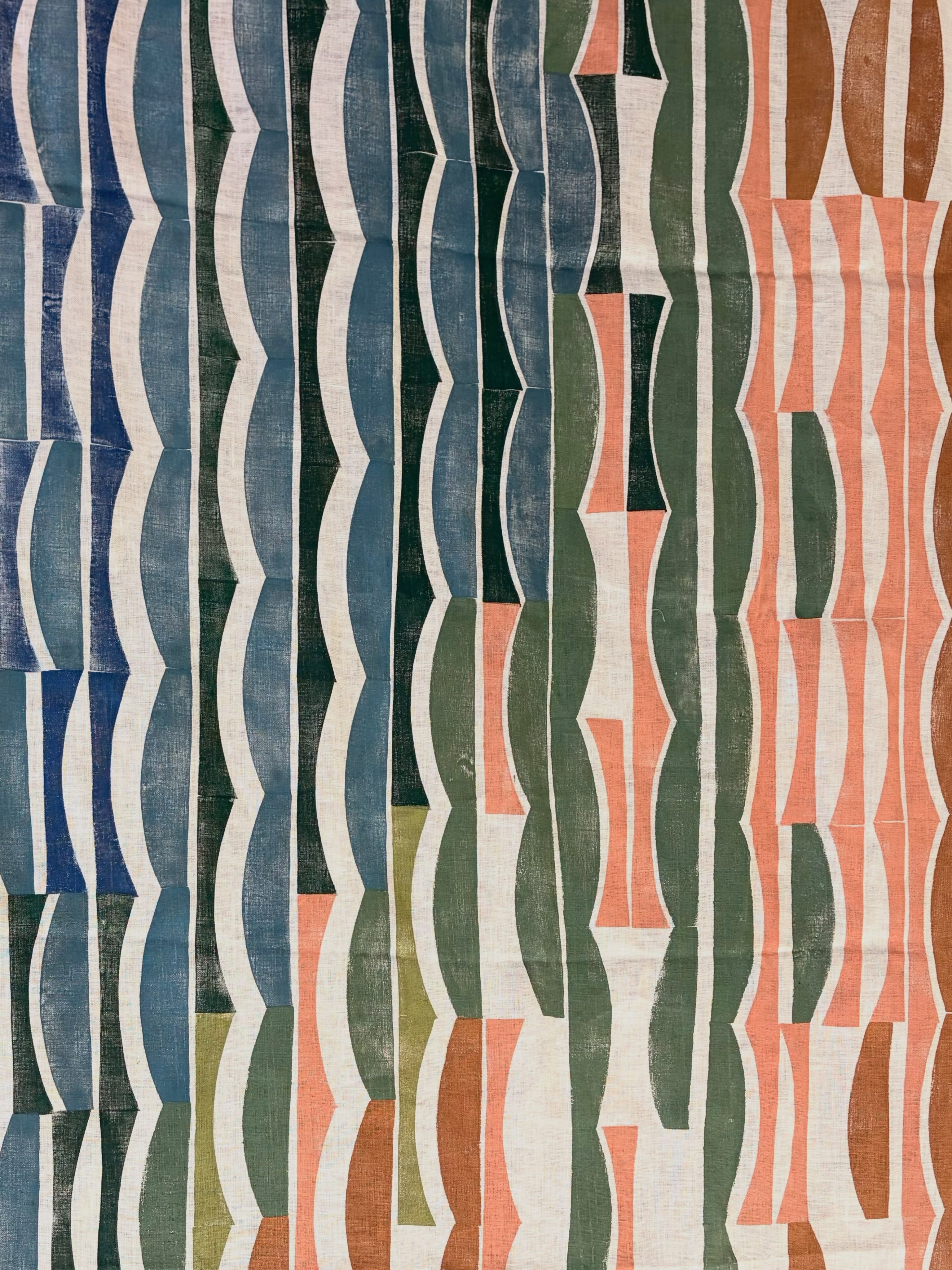 Hand block-printed fabric with repeating vertical blue, green, coral and brown geometric stripes.