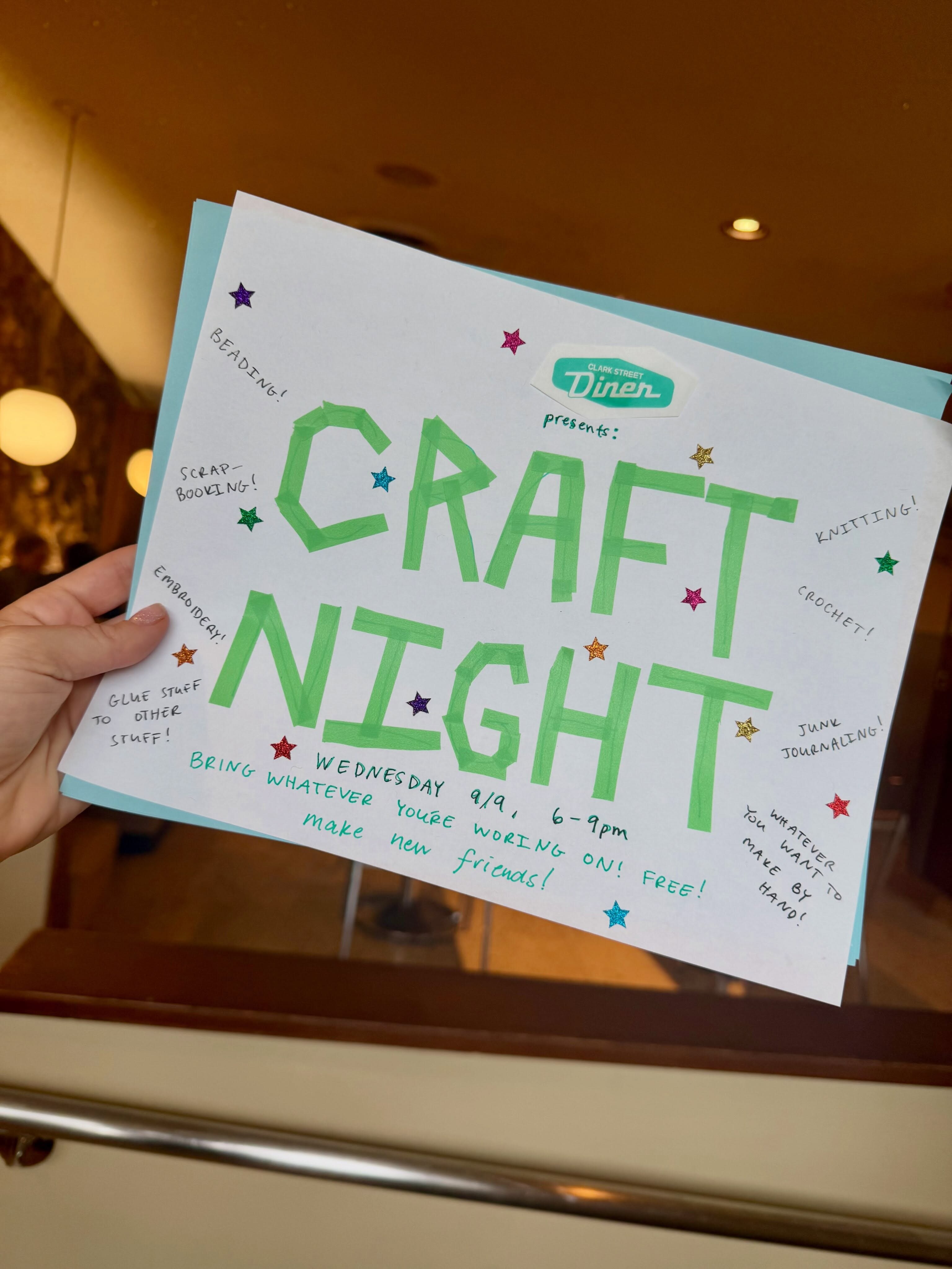 Hand-held green and white Craft Night flyer at Clark Street Diner