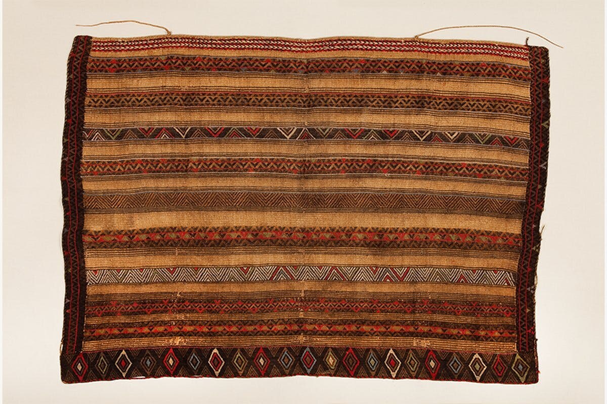 an intricate woven textile wall hanging in shades of brown and yellow and red