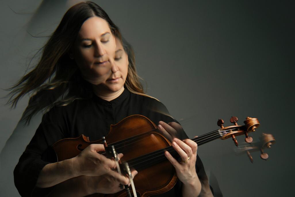 An overlaid image of Nadia Sirota wearing a black top, playing the viola in front of a grey background. The image is tripled with overlay.