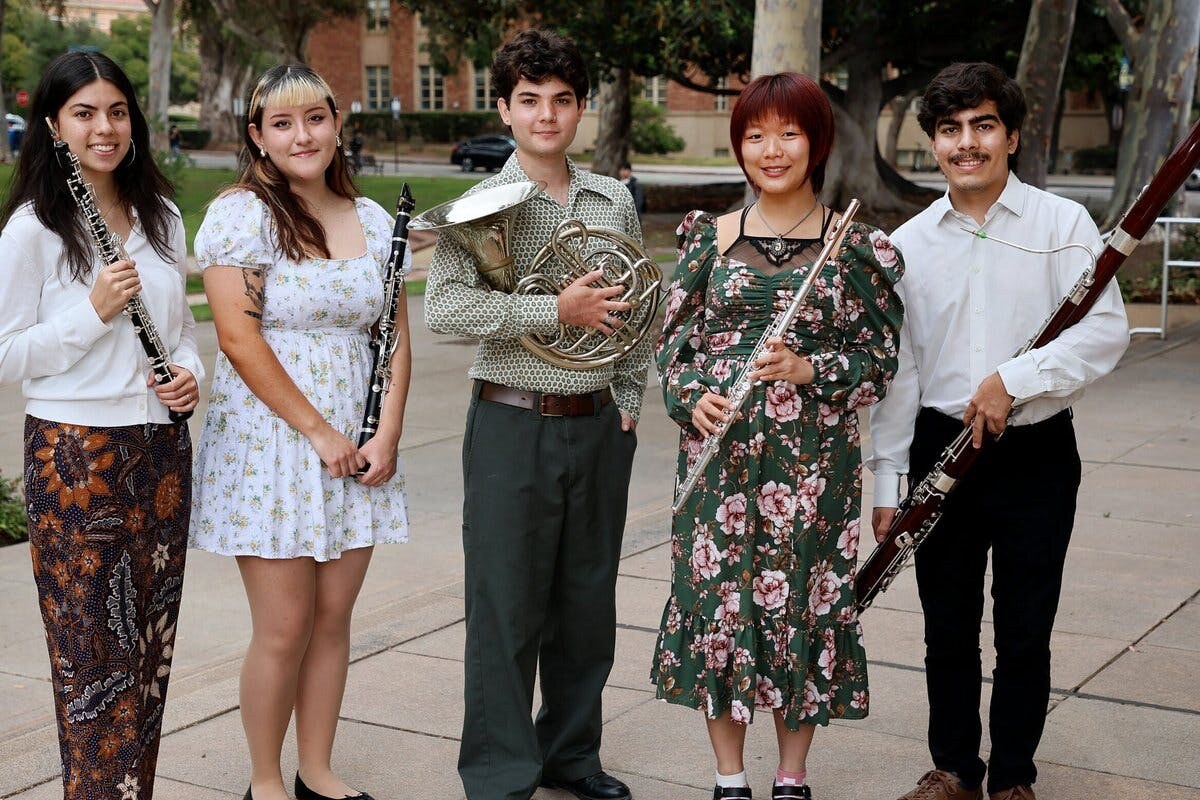 A quintet of musicians pose with their instruments