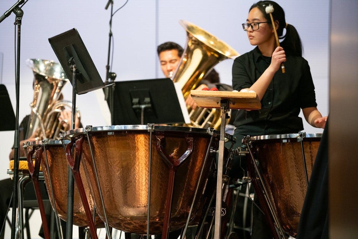 Close up of a timpani player on stage with an orchestra
