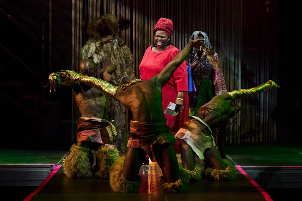 Performers in a circle formation in tribal outfits on stage for "Nkoli: A Fierce and Fabulous Life"